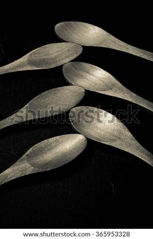 Wooden spoons on a plate of slate on a black background. Toned.