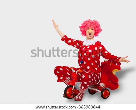 Funny clown in pink wig on a children's bike