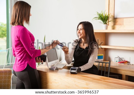 Profile view of a pretty young woman paying with a credit card at a store