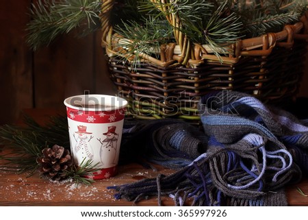 Winter still life with fir-tree and pine branches, a scarf and a paper glass with tea. Royalty-Free Stock Photo #365997926