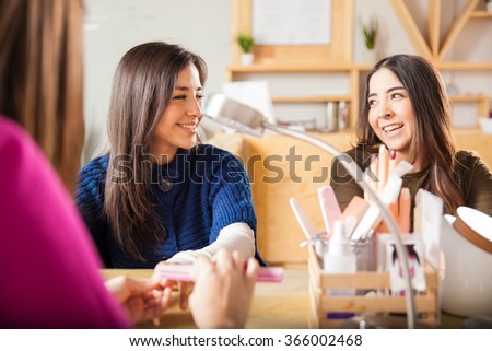 Beautiful Hispanic female friends having a good time together during their visit to a nail salon