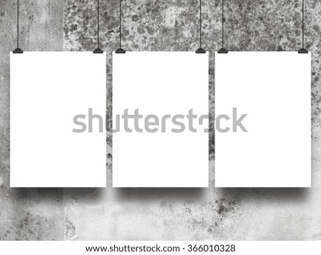 Close-up of three hanged paper sheets with clips on grey weathered concrete wall background