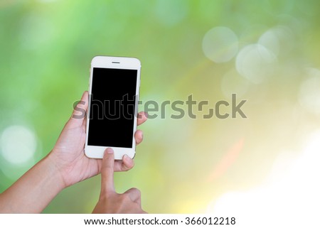 Hands woman are holding touch screen smart phone,tablet on blurred Green nature bokeh glitter defocused lights abstract background.
