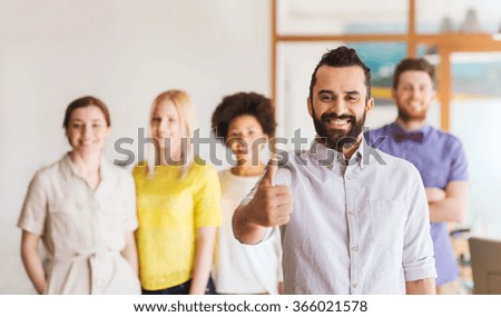 happy man showing thumbs up over team in office