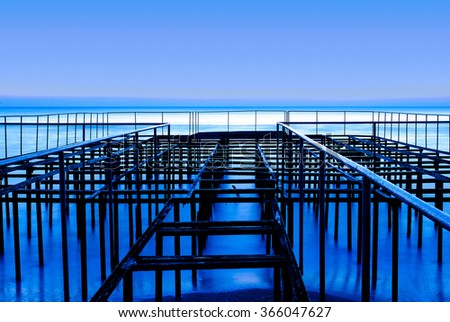 Abstract construction on the shore of the blue sea and clear sky at dawn. Background object.
