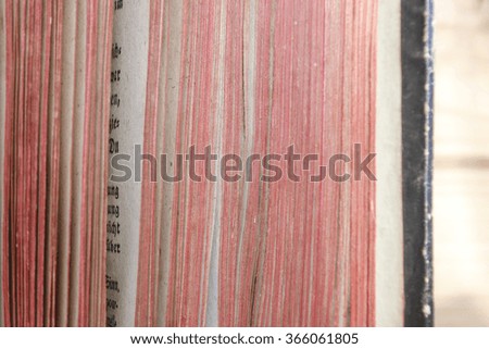 vintage open book with the red edges on blurred wooden background . Closeup