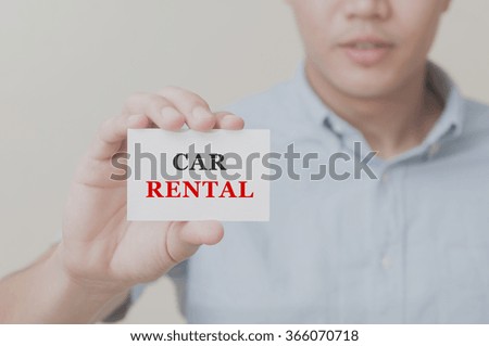 Man's hand showing Car Rental text on the card business card - closeup shot on white background.