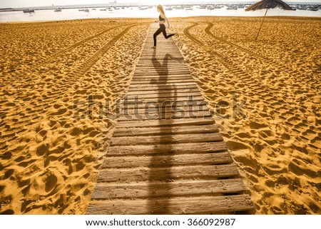 Woman in sport clothes taking off her shoes standing on the sandy beach footpath