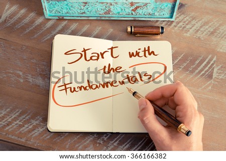 Retro effect and toned image of a woman hand writing a note with a fountain pen on a notebook. Handwritten text  START WITH THE FUNDAMENTALS, business success concept Royalty-Free Stock Photo #366166382
