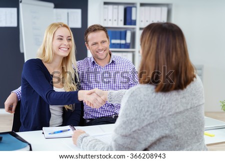 Happy couple shaking hands with a female business broker or investment adviser as they attend a meeting in her office Royalty-Free Stock Photo #366208943
