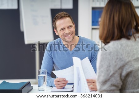 Attractive informal young businessman with a friendly smile discussing paperwork with a female colleague in the office Royalty-Free Stock Photo #366214031