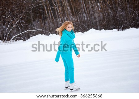 Side view of young woman skating on ice rink and looking at camera