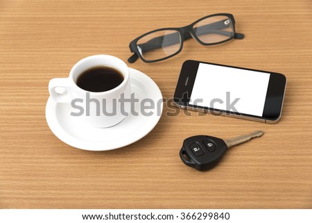 coffee cup and phone with car key on wood background