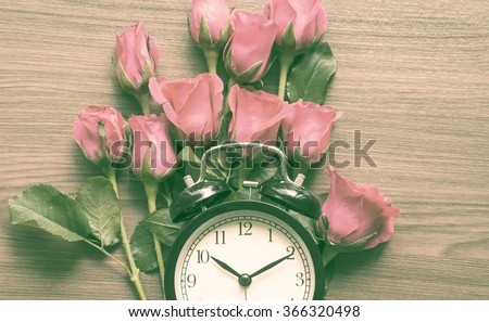 Clock on wooden background with pink roses vintage filter background