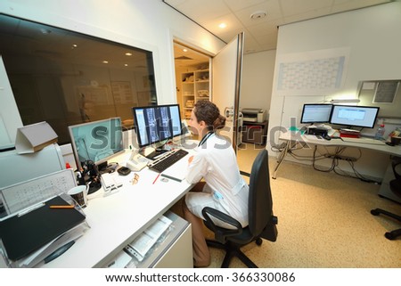 Experienced doctor looking at MRI scan of lumbar region on Monitor in control room