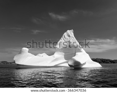 Black and White picture of an iceberg in front of a rocky island in Newfoundland and Labrador, Canada