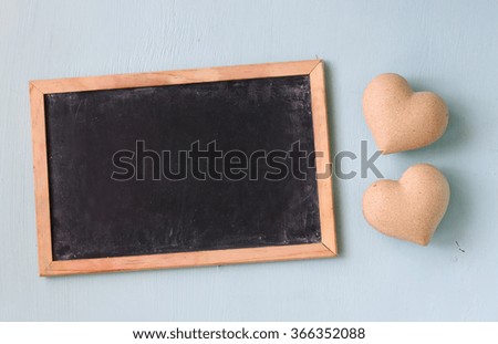top view image of wooden hearts next to blackboard on wooden light blue background. valentine's day celebration concept
