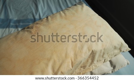 Dirty pillow  with pale yellow and brown color from saliva stain on the bed.