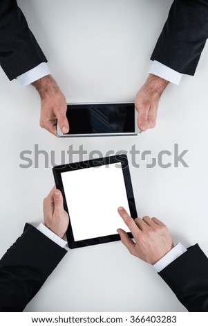 Cropped image of businessmen using digital tablets at white table in office