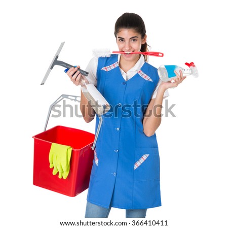 Portrait of confident female worker carrying bucket with cleaning equipment against white background