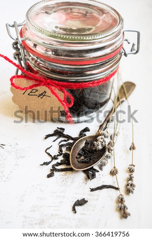Black tea leaves in the jar with tag on rustic background