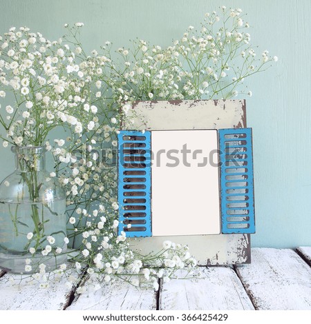 old wooden frame next to white flowers on wooden table. template, ready to put photography
