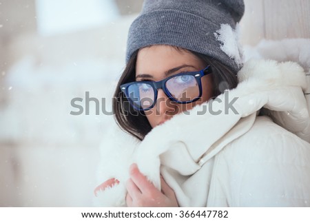 Winter outdoor close up portrait of beautiful girl with hat and glasses. Fashion photo.