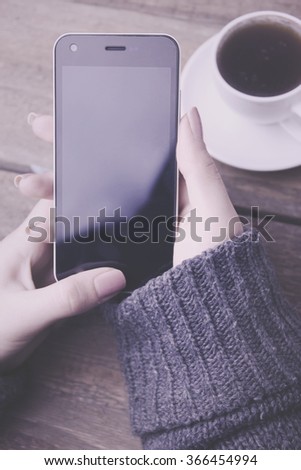 phone in hand woman on wooden table