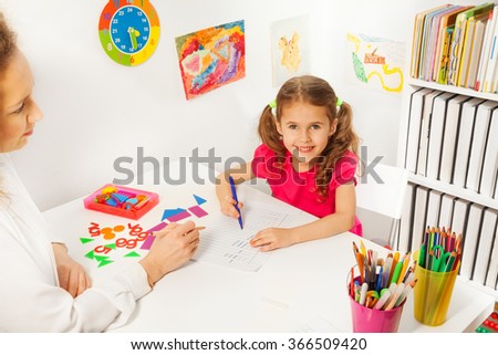 Preschool teacher helping pupil with class work