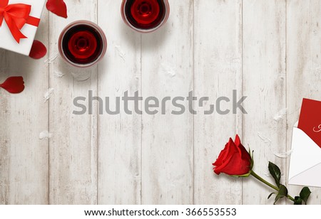 Valentines day romantic background with glasses of wine, gift, envelope, rose on wooden table.