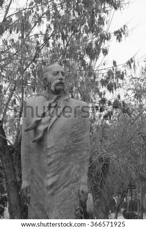 A stone statue of a man on the background of trees. Black white picture
