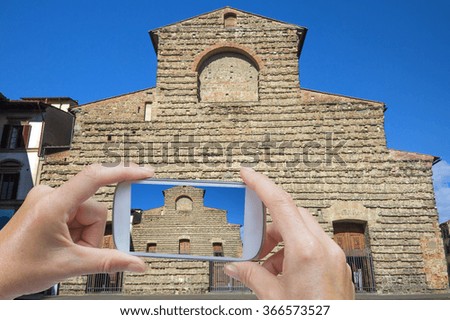 In the left bottom of the photo are hands holding smart phone and taking picture of famous Sagrestia Vecchia in Florence (Tuscany, Italy). 