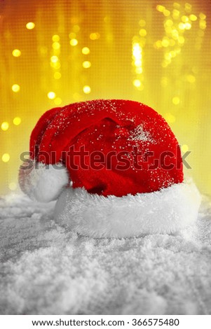 Santa Claus hat on a snowy table over glitter background