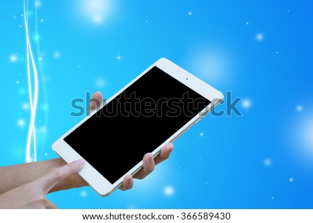 Hands woman are holding touch screen White Tablet on blurred blue wave and glitter sparkle defocused rays lights bokeh abstract background.