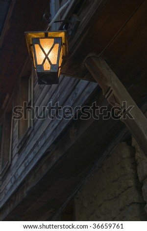 Old lantern hanging in front of the old wooden house.