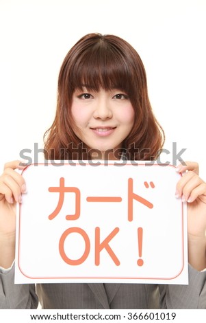 businesswoman holding a message board with the phrase CREDIT CARD ACCEPTED in Japanese