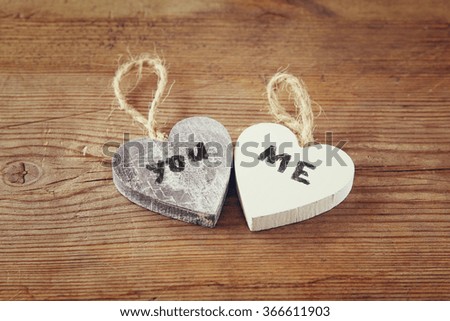 selective focus photo of couple of wooden hearts with words "you, me" written on them  on rustic table.  valentine's day celebration concept. vintage filtered