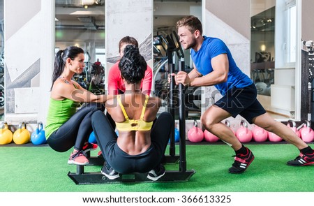 Man pushing women on cart as fitness exercise in gym