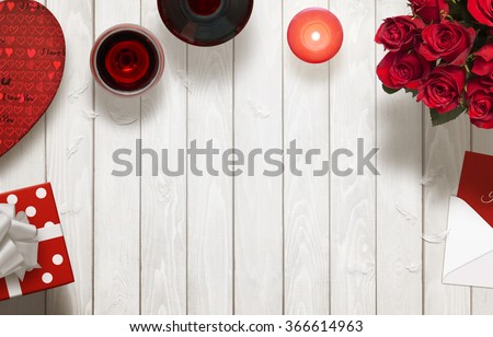 Valentines day romantic background with gifts, glasses of wine, candle, roses, envelope on wooden table.