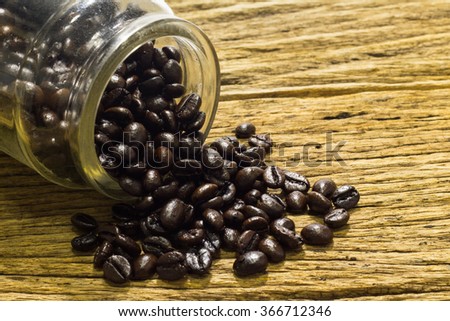 Glass of coffee beans wooden background