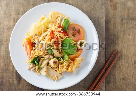 noodles with vegetables In white plate placed on a wooden table, top view