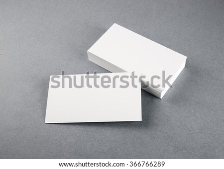 Photo of blank business cards with soft shadows on gray background. Mock-up for branding identity. Studio shot.