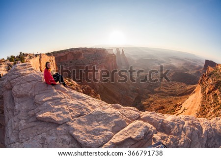 Girl sitting at the Mesa Arch at sunrise, Canyonlands National Park, Utah Royalty-Free Stock Photo #366791738