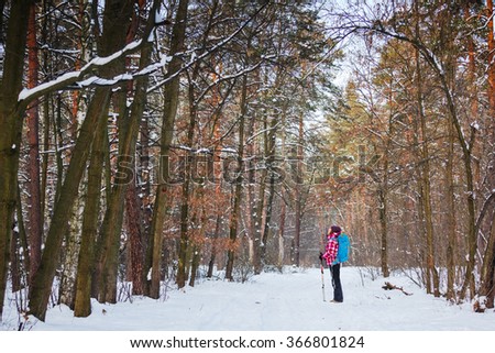Hiker in winter forest. Sport, inspiration and travel. Young happy woman cross country walking in mountains on snow winter day.