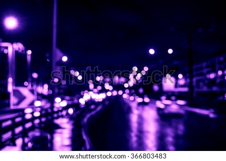 Rainy night in the big city, cars driving on highway. Defocused image, image in the purple-blue toning