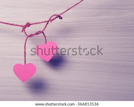 Two paper hearts hanging on a rope.