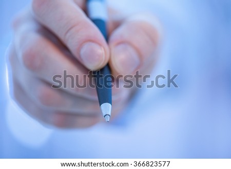 Businessman's hand holding a pen, blue background