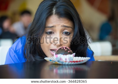 Closeup portrait of desperate woman in blue shirt craving fudge with pink sprinkles dessert, eager to eat, isolated indoors background Royalty-Free Stock Photo #366828365