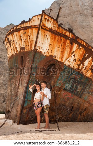 portrait of a young couple in a beach with an old shipwreck 