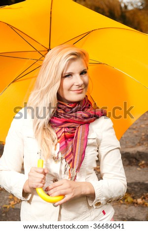 Picture of a young beautiful girl in a colorful scarf with umbrella  in an autumn park